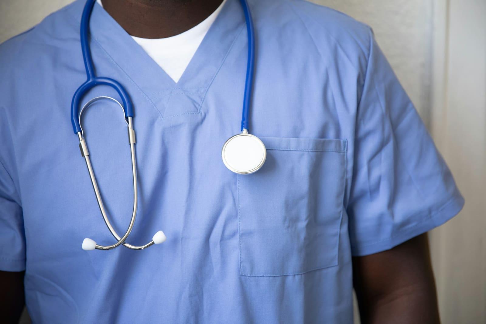 A clinician in blue scrubs with a stethoscope around the neck.