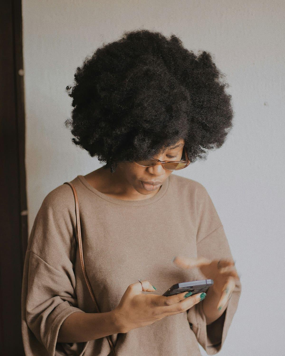 A woman looks down at the phone in her hands.